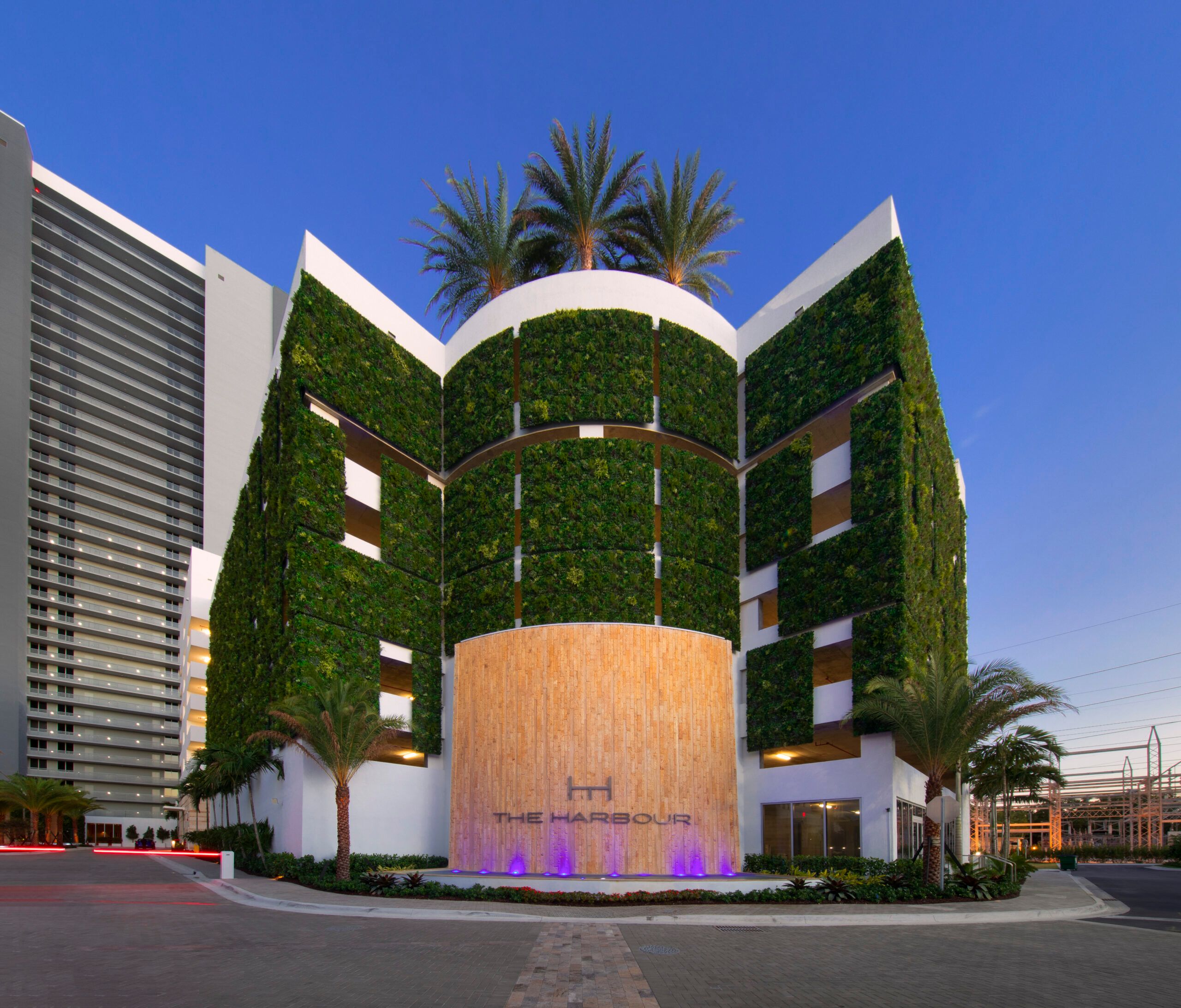 The Harbour's illuminated entrance and living-wall facade at dusk